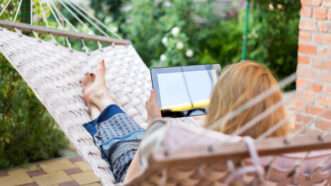 Someone relaxes in a hammock while holding a tablet | Photo 75548832 © Maxim Kostenko | Dreamstime.com