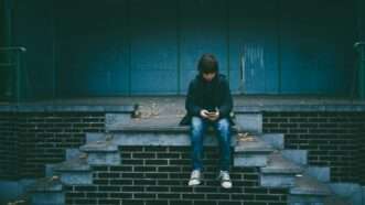 Child sitting outside on a smartphone | Photo by <a href="https://unsplash.com/@gaellemarcel?utm_content=creditCopyText&utm_medium=referral&utm_source=unsplash">Gaelle Marcel</a> on <a href="https://unsplash.com/photos/boy-sitting-on-concrete-stairs-FLdK5N-YGf4?utm_content=creditCopyText&utm_medium=referral&utm_source=unsplash">Unsplash</a>       