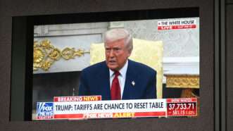 President Donald Trump speaking in the White House, as seen on Fox News, with a stock ticker along the bottom showing precipitous declines. | Anthony Behar/Sipa USA/Newscom