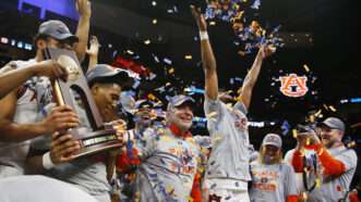 The Auburn basketball team (and others) wearing hats and t-shirts that say FINAL FOUR on them. One player is holding a trophy and another is throwing confetti in the air. | MIKE ZARRILLI/UPI/Newscom